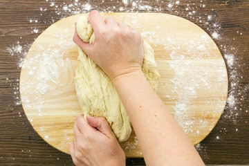 Woman kneading dough on floured board, above