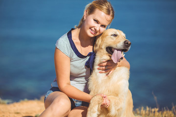 Beautiful woman with her dog playing on the sea shore. Outdoor p