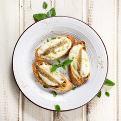 Crostini with fish, mozzarella and oregano