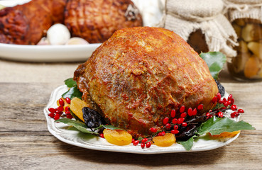Baked pork with fruits on wooden table.