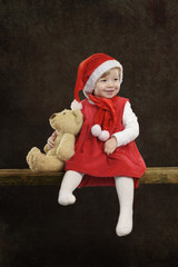 little girl with christmas hat and teddy bear on black