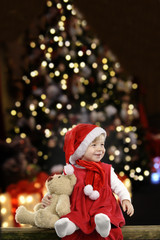 Fototapeta na wymiar little girl with christmas hat and teddy bear on black