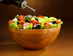 oil pouring into bowl of vegetable salad