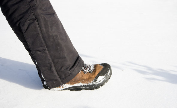 Female leg makes step in winter pants and shoes on snow