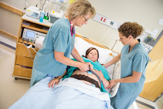 Nurses Preparing Pregnant Woman For Fetal Heart Rate Monitor