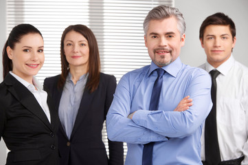 senior businessman standing on foreground and smiling.