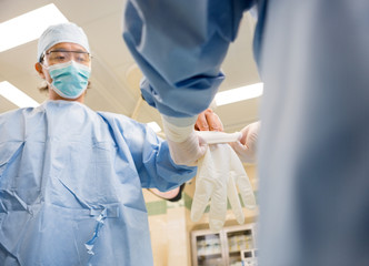 Nurse Assisting Surgeon In Wearing Glove