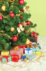Fototapeta na wymiar Decorated Christmas tree with gifts on green wall background