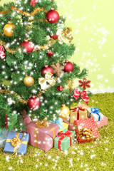 Decorated Christmas tree with gifts on green wall background