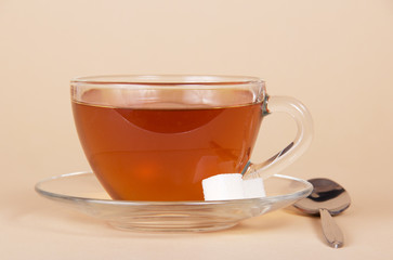 Transparent cup with tea, saucer and spoon