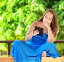 Young woman reading e-book. Outdoor portrait