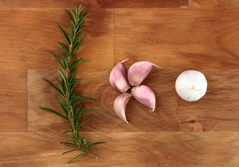 Garlic and  fresh organic rosemary on wooden chopping board