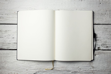 Open blank notepad with empty white pages laying on a wooden tab