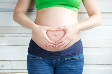 Female showing heart sign with hands infront of pregnant stomach