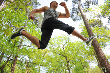 Athletic man jumping in forest