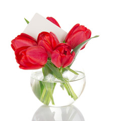 Bouquet of red tulips in round vase and empty card