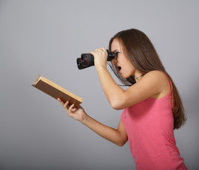 Girl looking through binoculars on a book