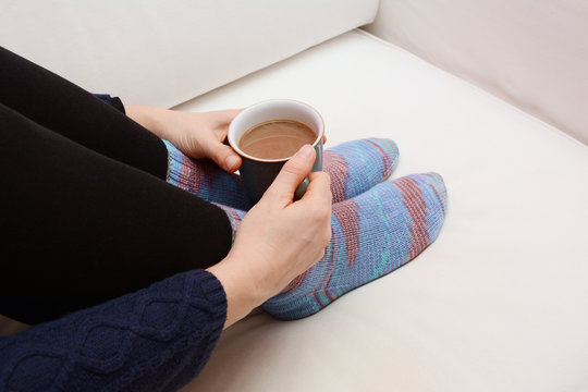 Woman's Hands Holding A Hot Beverage, Sitting On A Couch