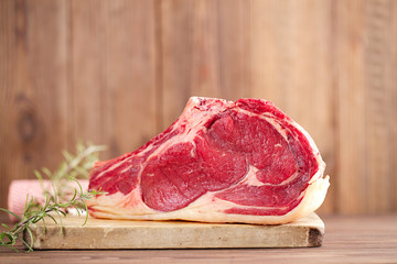 raw beef Rib steak with bone on wooden board and table