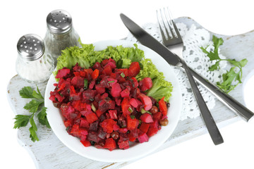Beet salad on plate on napkin on wooden board isolated on white