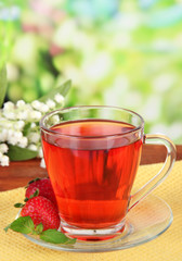 Delicious strawberry tea on table on bright background