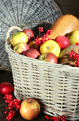 Juicy apples and pumpkin in wooden basket on table close-up