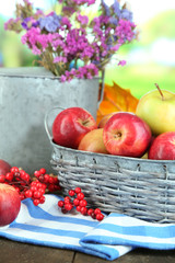 Juicy apples in basket on table on natural background