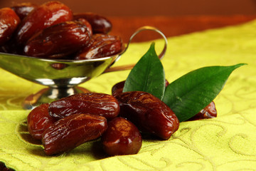 Dried dates in metal dish on fabric background