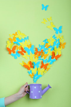 Paper butterflies fly out of watering can