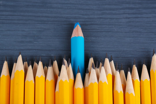 Celebratory pencil among usual pencils, on color background