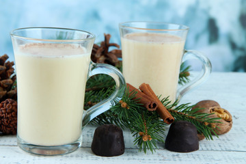 Cup of eggnog with fir branches and candies