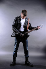 Fototapeta premium Young musician playing guitar on gray background