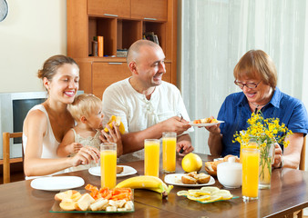 Portrait of cheerful three generations family eating  friuts wit