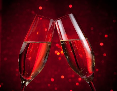 two champagne flutes on red dark light bokeh background