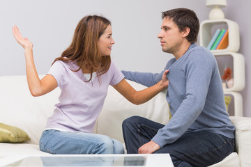 Young woman about to slap man in the living room at home
