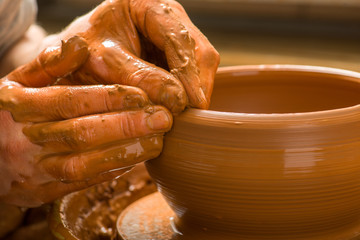hands of a potter, creating an earthen jar on the circle