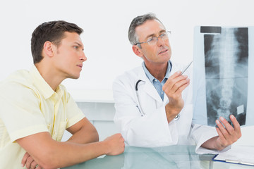 Fototapeta premium Doctor explaining spine x-ray to patient in office