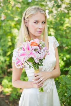 Blonde bride holding bouquet smiling at camera