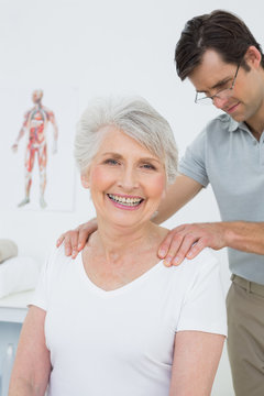 Male physiotherapist massaging a senior woman's shoulders