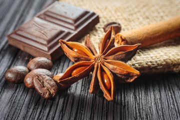 Chocolate bar and spices on wooden table