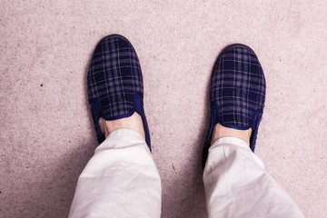 Feet wearing slippers on carpet