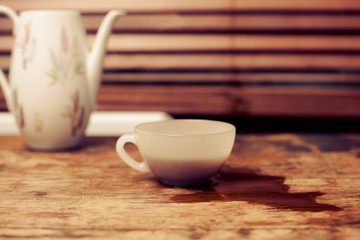 Coffee cup and pot by window on wood table