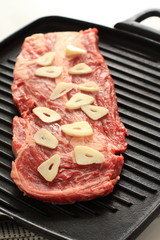 raw steak and garlic on grill pan