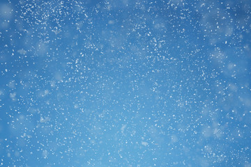 Fototapeta premium Falling snow over blue background with copy space