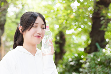 Obraz premium young asian woman holding bottle of water in the park
