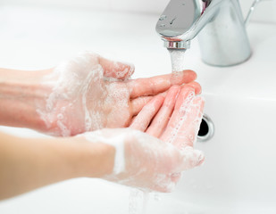 Washing of female hands with soap in bathroom close up
