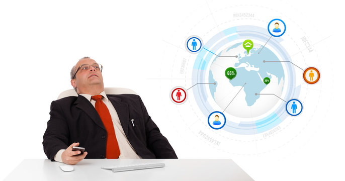 businessman sitting at desk and holding a mobilephone with globe