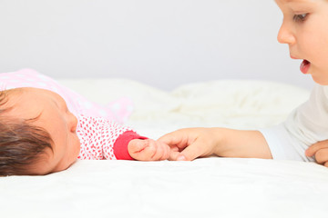 little boy holding newborn sister by hand
