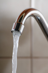 Vertical image of a tap with water flowing normally