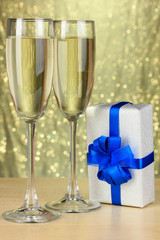 Glasses of champagne with gift box on shiny background